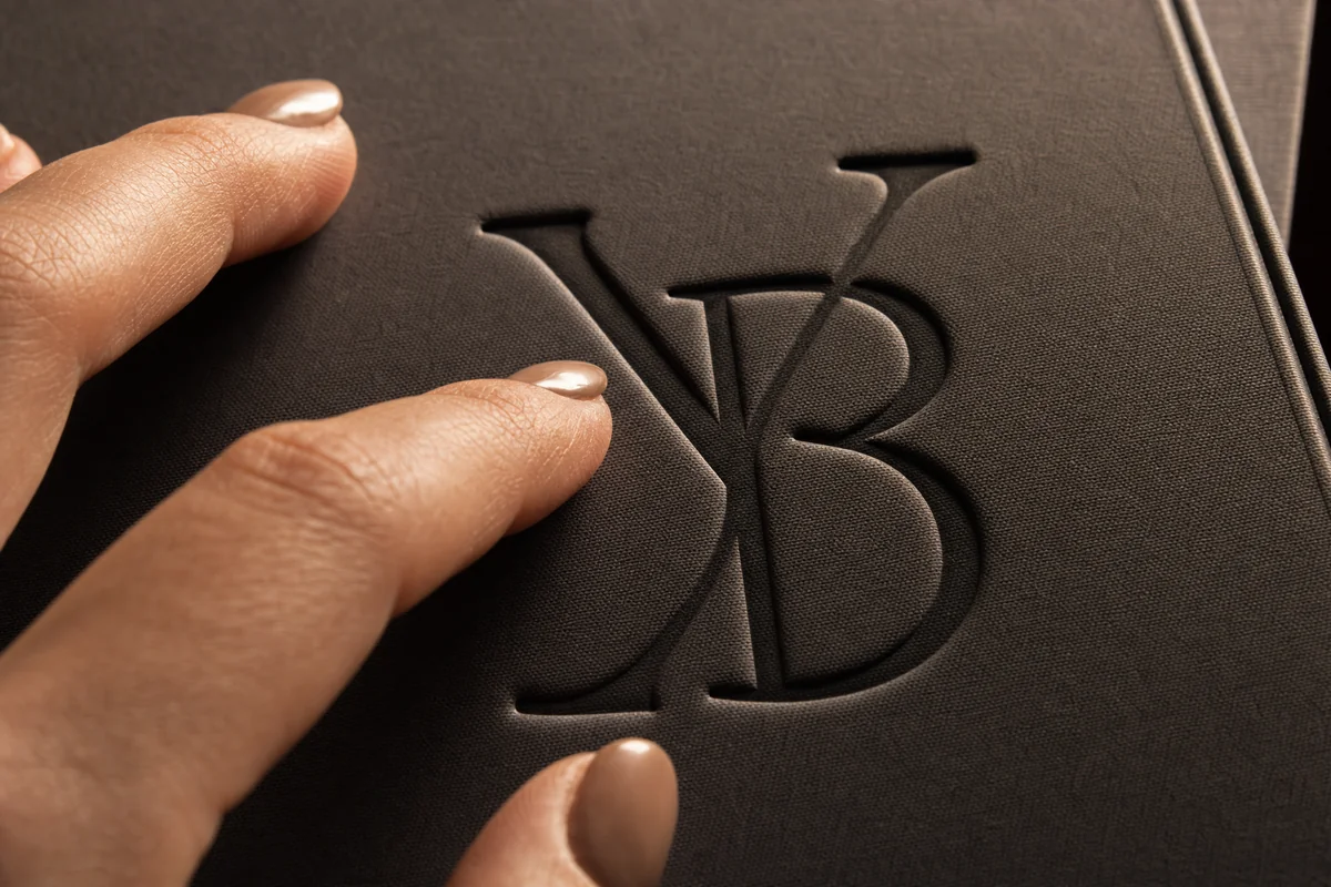 Close-up of a debossed logo on a hardcover book, showing depth and shadow play