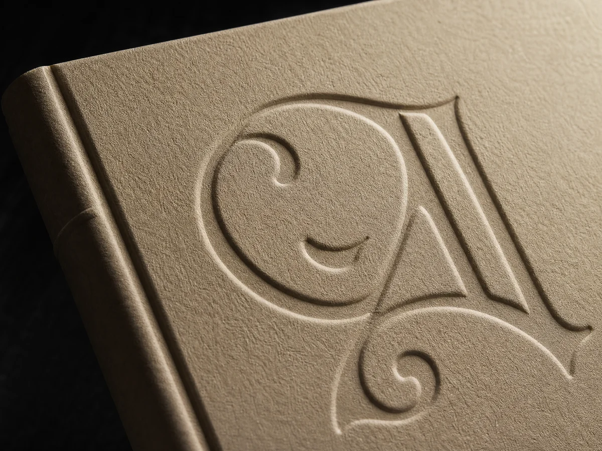 Debossed title lettering on textured special paper book cover showing sunken relief effect with dramatic side lighting