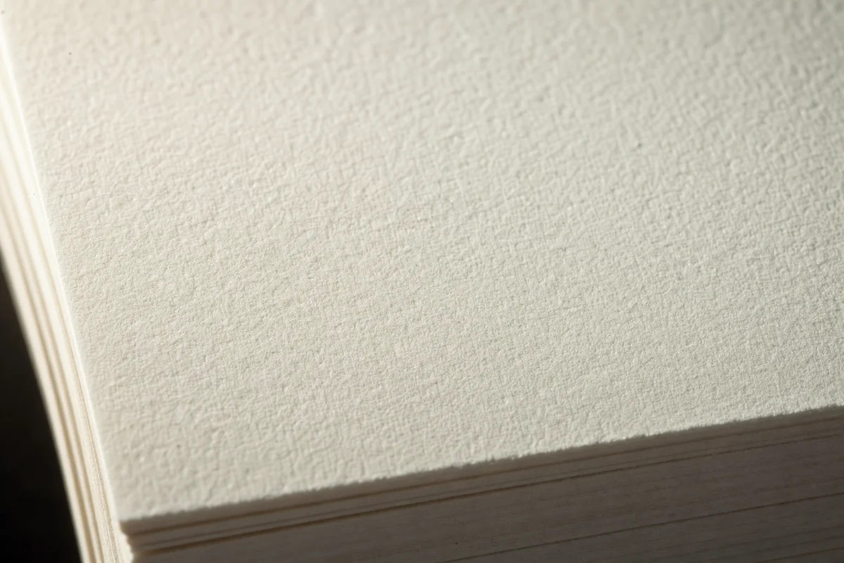 Stack of uncoated offset paper sheets showing natural fiber texture
