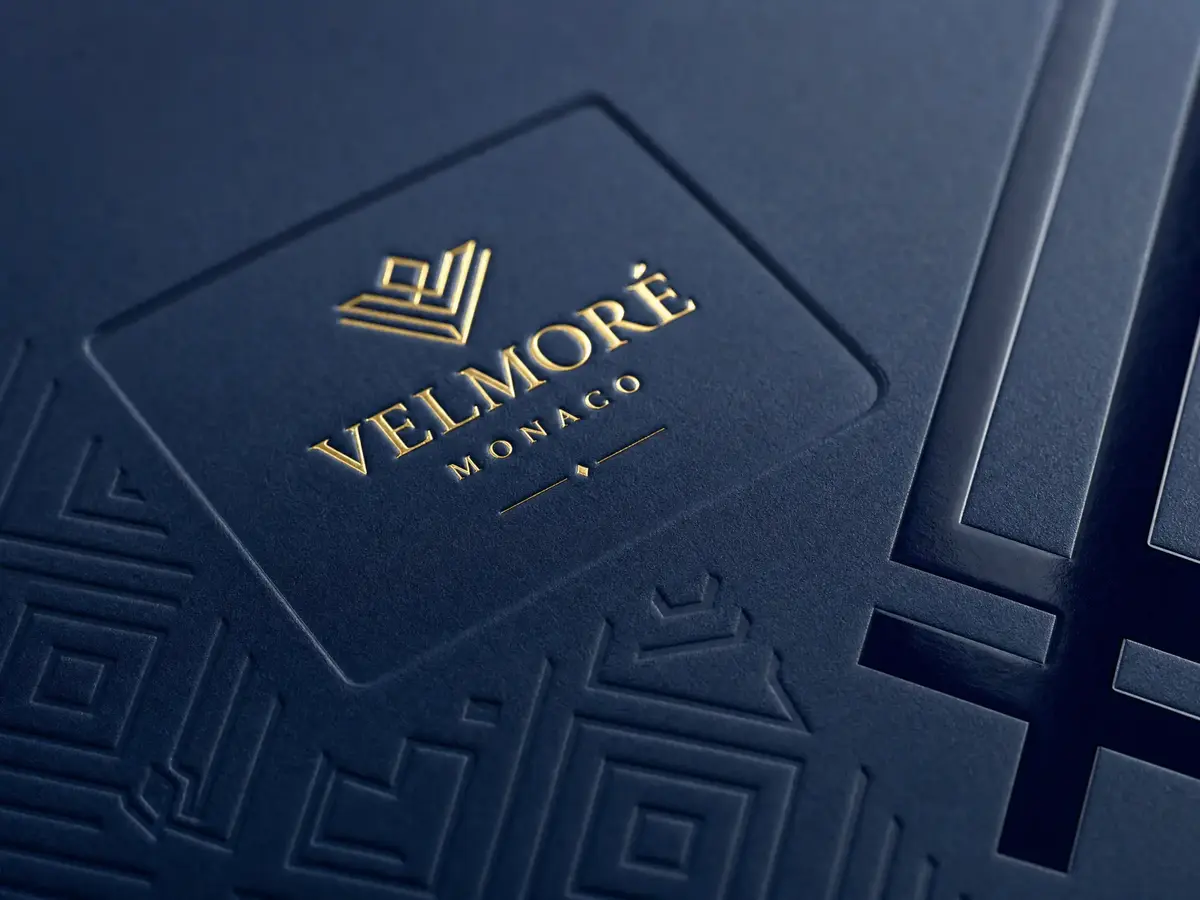 Close-up detail of luxury box finishing techniques: gold foil stamping on navy paper, embossed logo area, and spot UV gloss effect