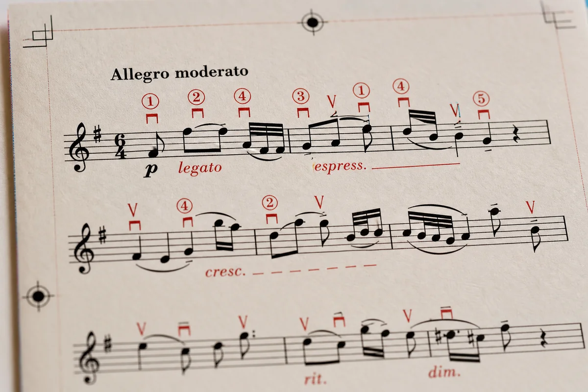 Close-up of a two-color music score page showing black notation with red editorial finger markings