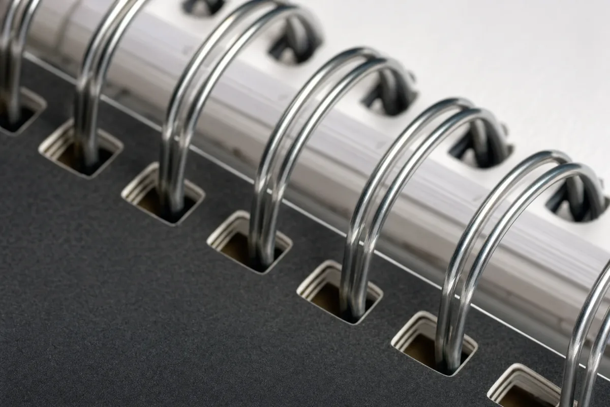 Close-up detail of wire-o twin-loop binding on a planner showing 2:1 pitch and metal finish options